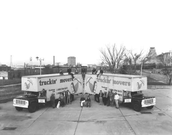 Doug Carlton and co-founder standing between Truckin' Movers trucks in 1976