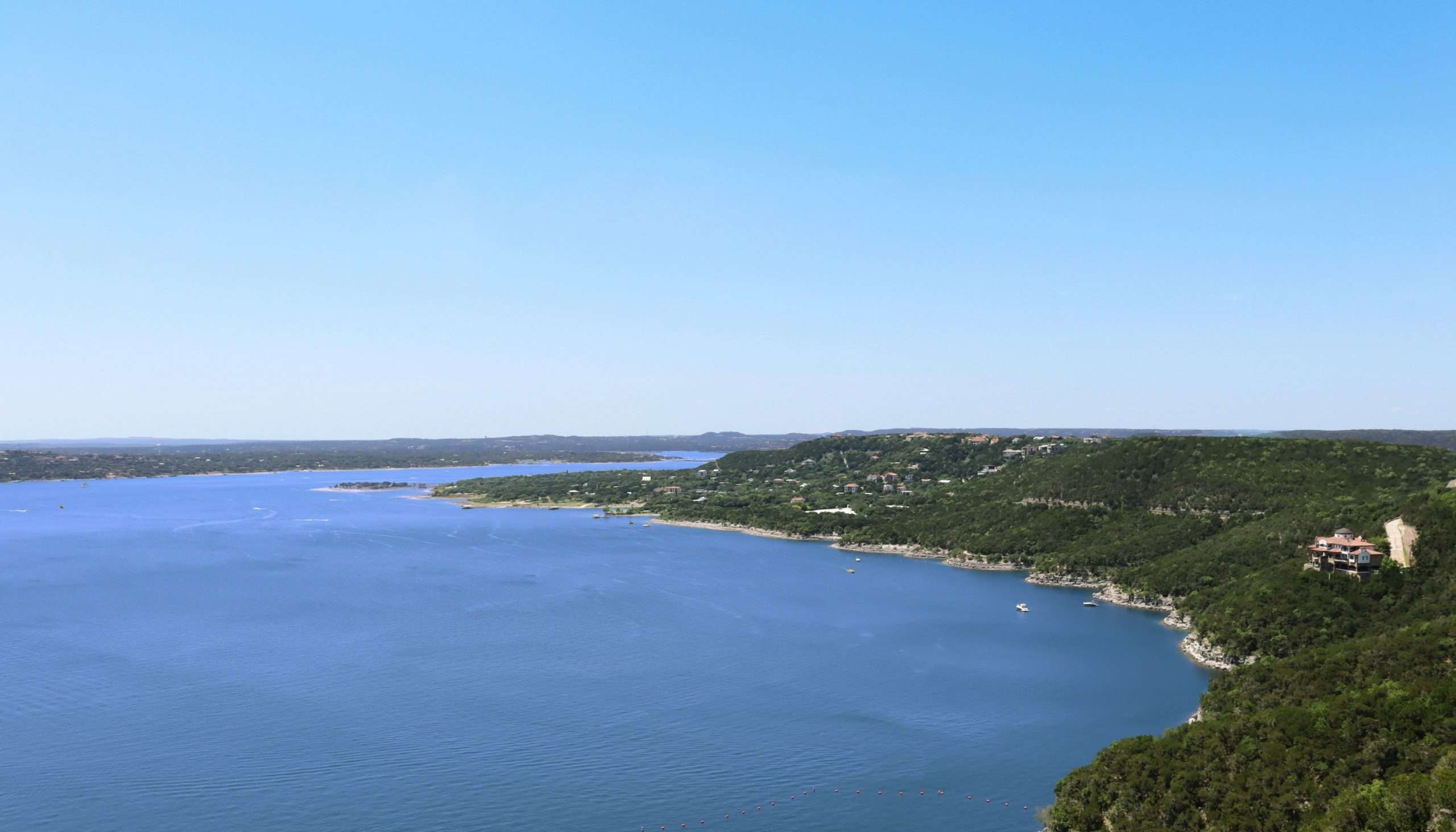 dale-honeycutt-Vqco2uwrXq8-unsplash View of lake with trees and blue sky.