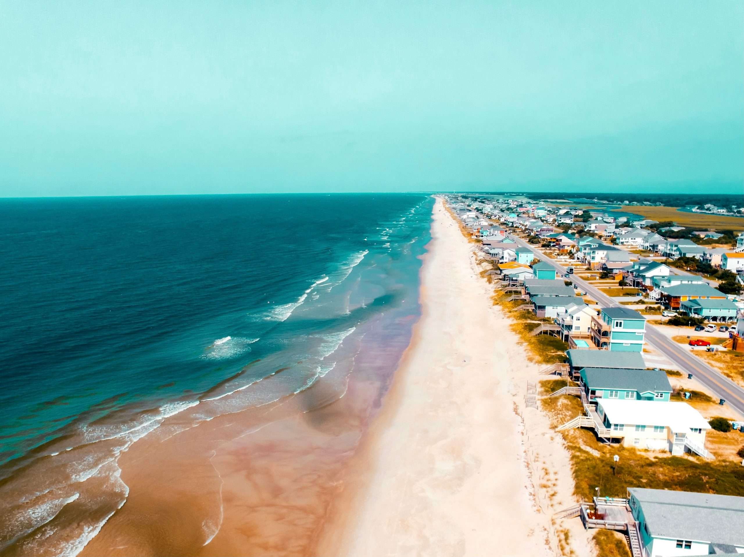 parsa-mahmoudi-8bI4yPvh_ao-unsplash Coastal beach with houses along the shoreline.