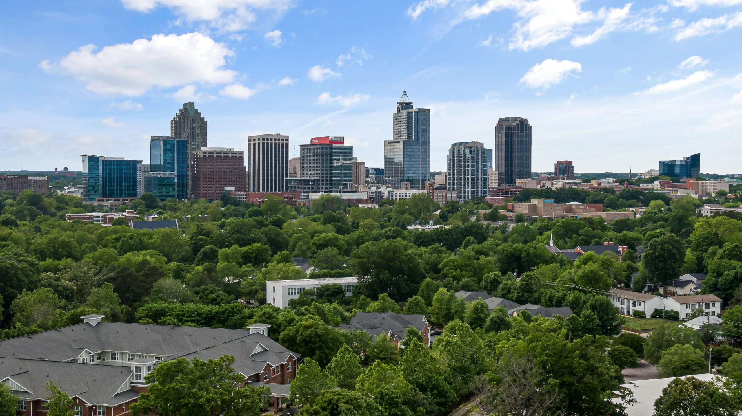 pexels-curtis-adams-1694007-12119358 Raleigh skyline with green trees and skyscrapers.