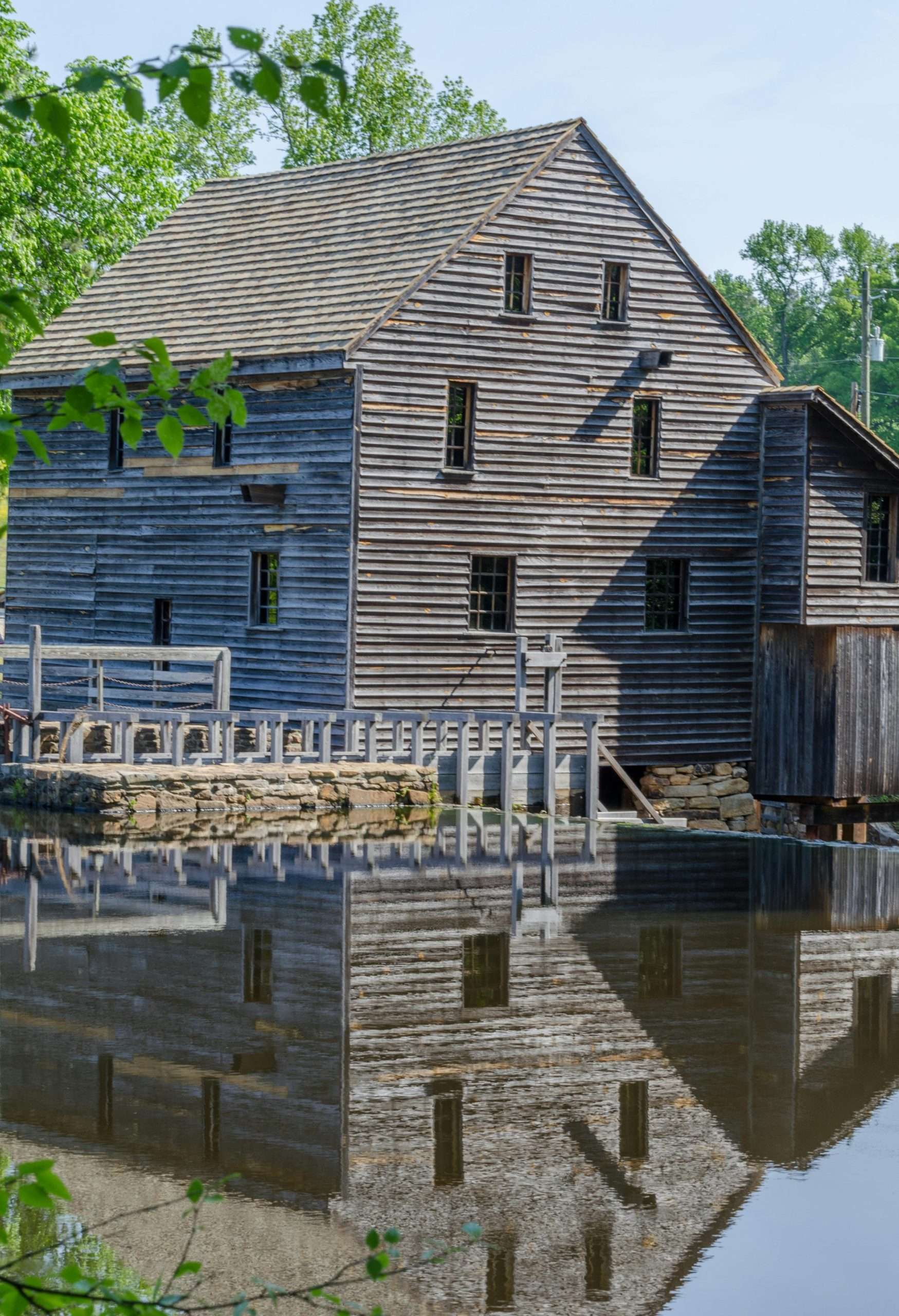 pexels-joseph-fuller-3673812-5603625 Historic wooden mill reflecting on calm water.
