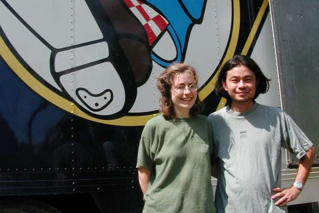 Two people smiling in front of airplane graphic.